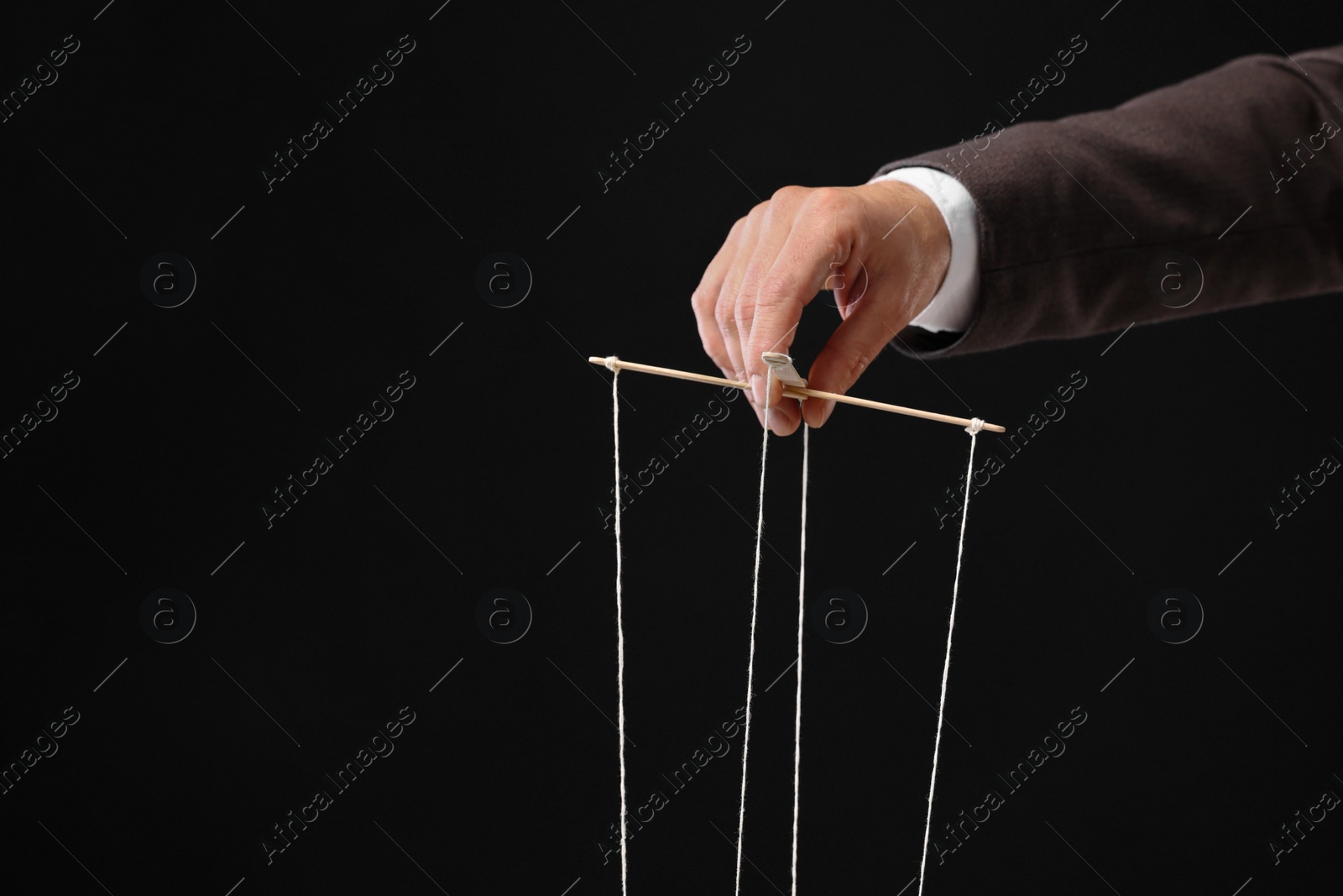 Photo of Man pulling strings of puppet on black background, closeup. Space for text