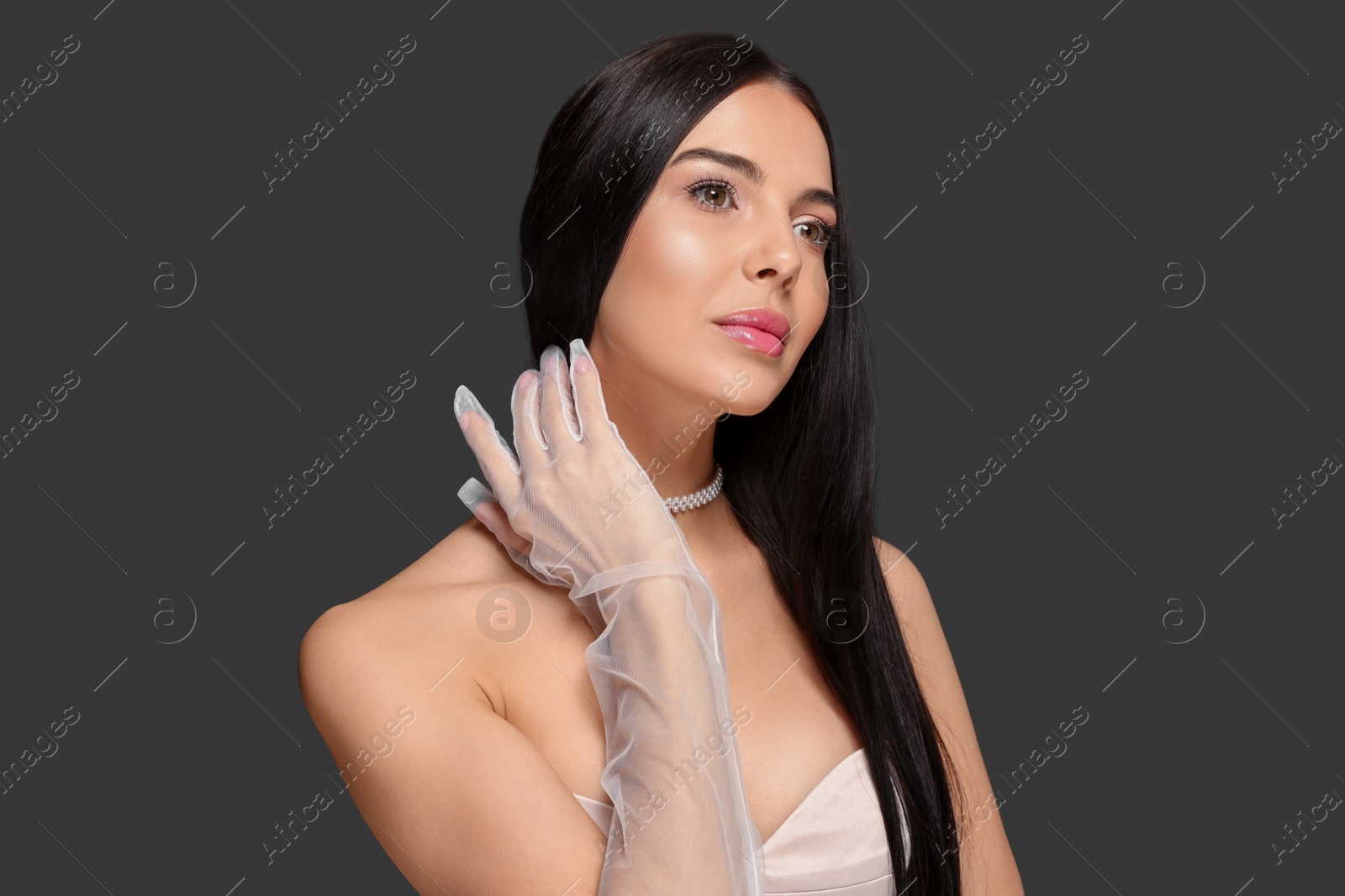 Photo of Portrait of beautiful young woman in evening gloves on black background