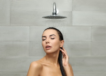 Photo of Beautiful young woman taking shower in spa center