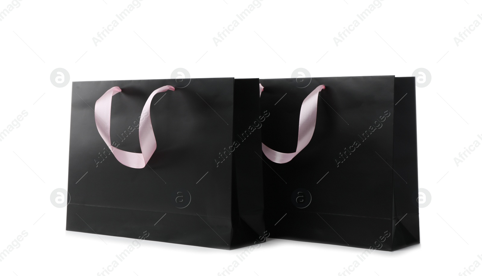 Photo of Paper shopping bags with ribbon handles on white background. Mockup for design