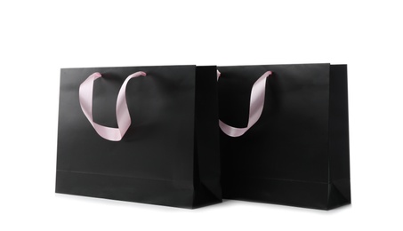 Photo of Paper shopping bags with ribbon handles on white background. Mockup for design