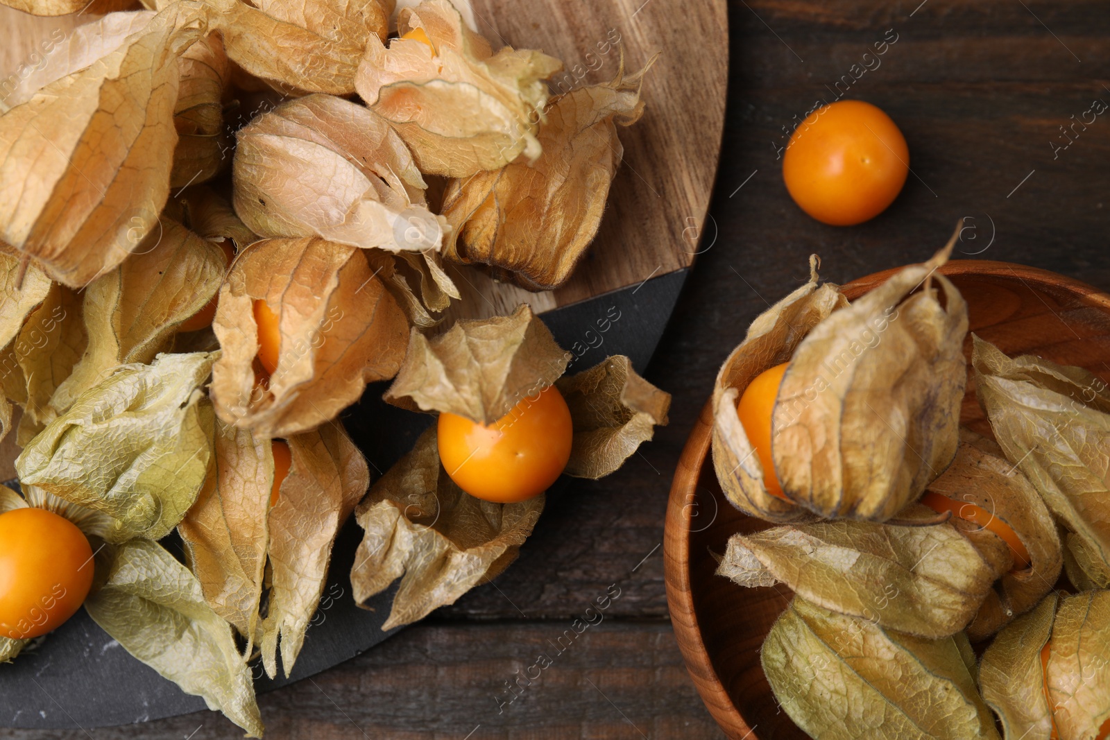 Photo of Ripe physalis fruits with calyxes on wooden table, flat lay