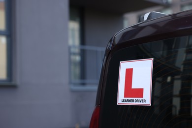 L-plate on car outdoors, closeup with space for text. Driving school