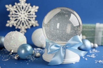 Photo of Beautiful snow globe and Christmas balls on blue background