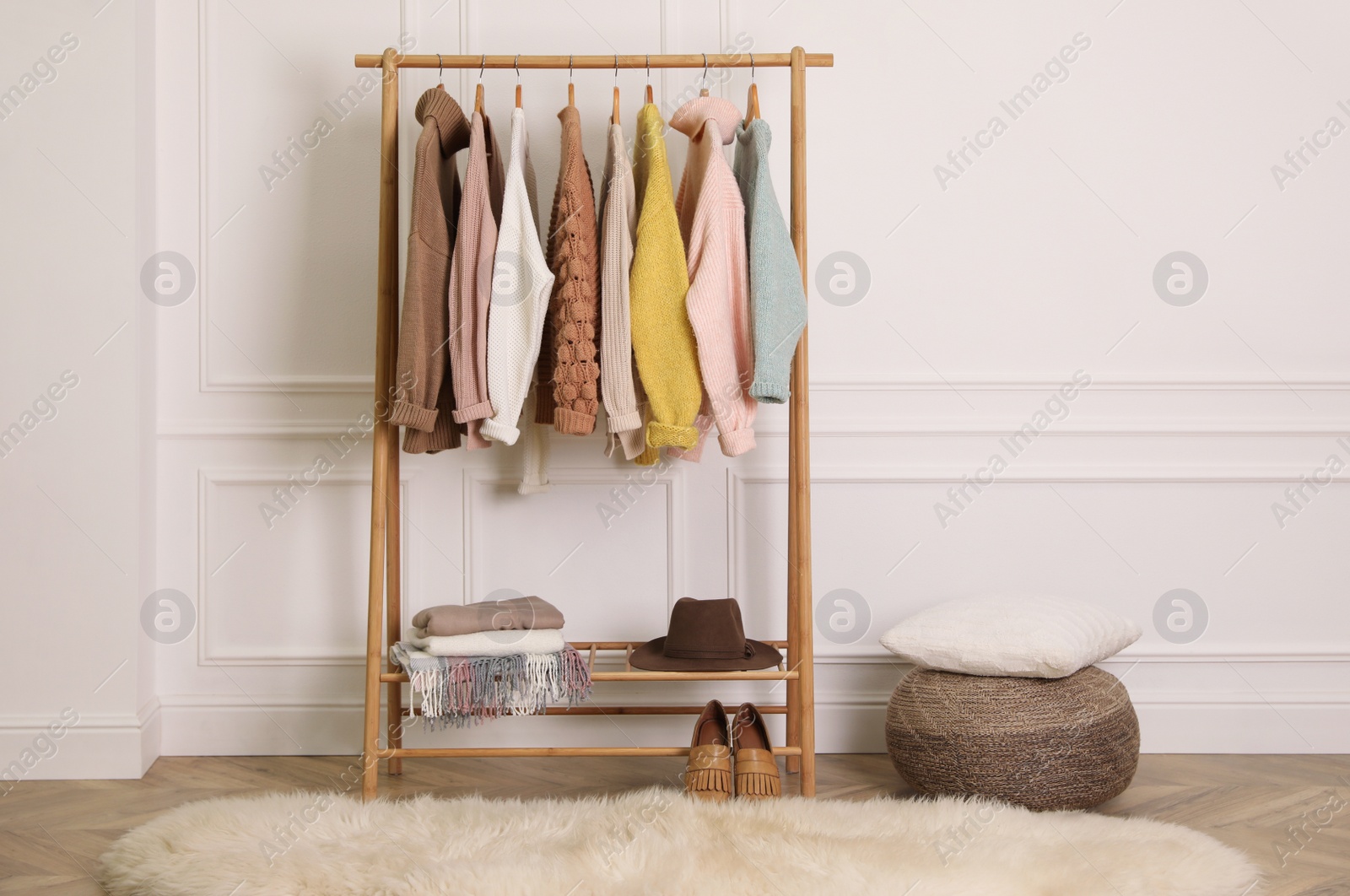 Photo of Stylish warm clothes on rack in dressing room interior