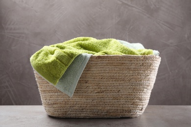 Photo of Towels in wicker laundry basket on grey table