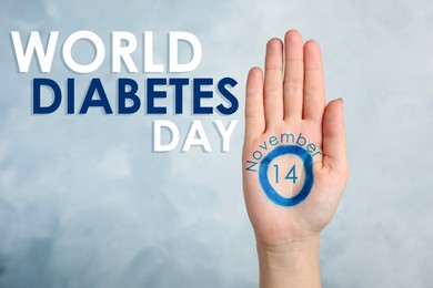 Image of Woman showing blue circle drawn on palm against color background, closeup. World Diabetes Day
