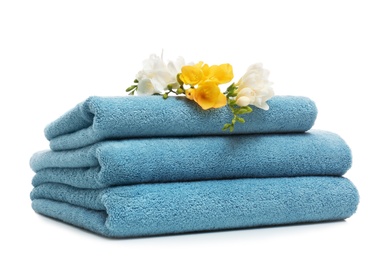 Stack of clean folded towels with flowers on white background