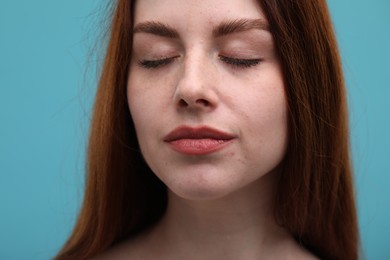 Photo of Portrait of beautiful woman with freckles on light blue background, closeup