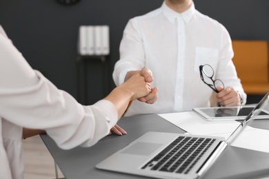 Photo of Human resources manager shaking hands with applicant during job interview in office