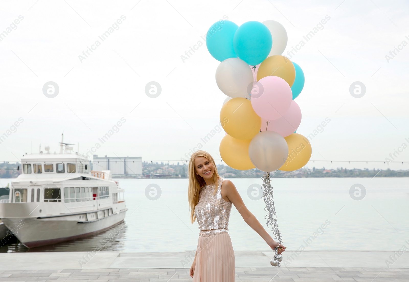 Photo of Beautiful young woman with bunch of balloons outdoors