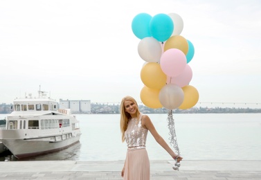 Photo of Beautiful young woman with bunch of balloons outdoors