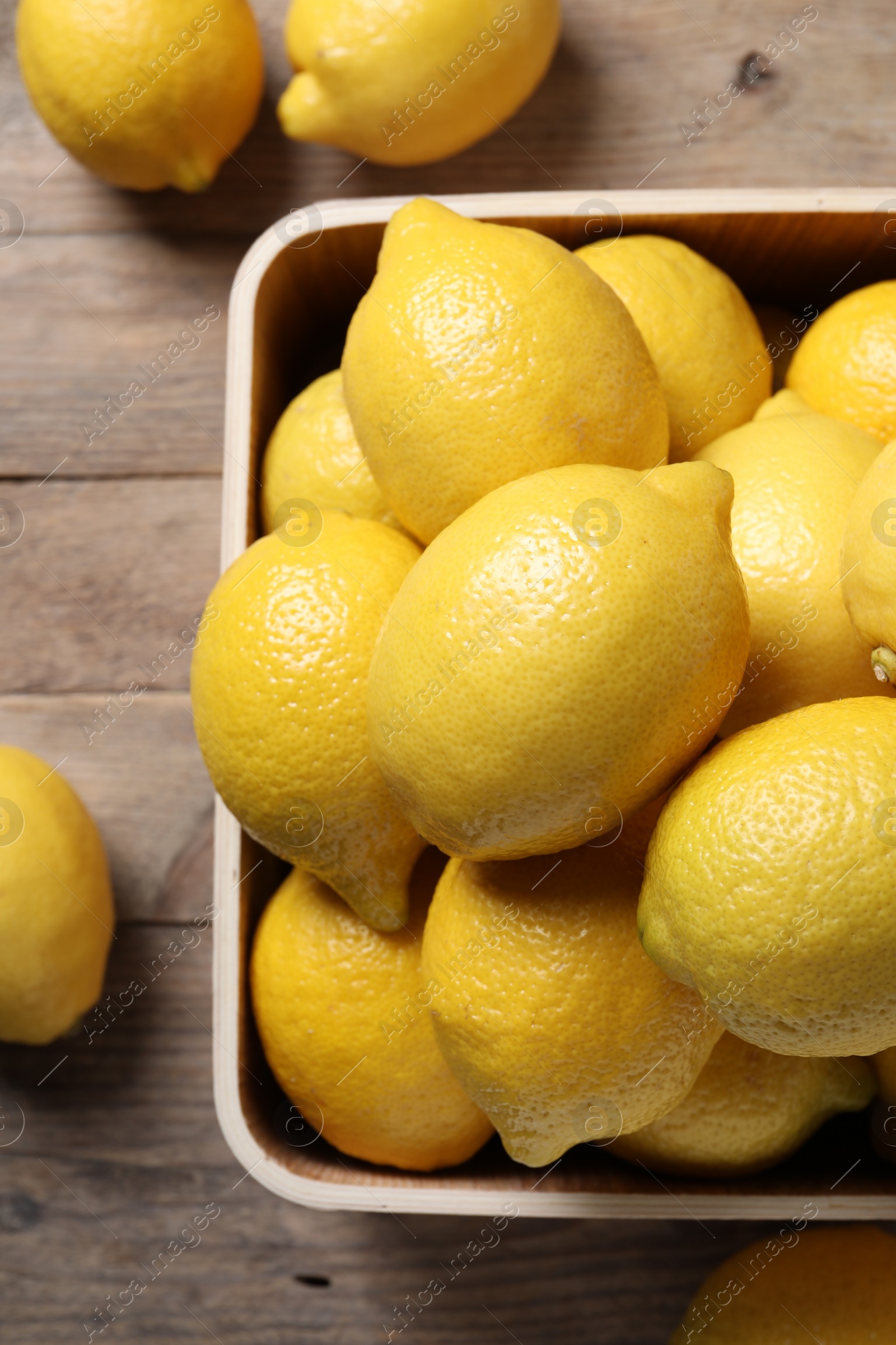 Photo of Fresh lemons in crate on wooden table