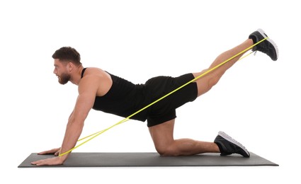 Photo of Young man exercising with elastic resistance band on fitness mat against white background