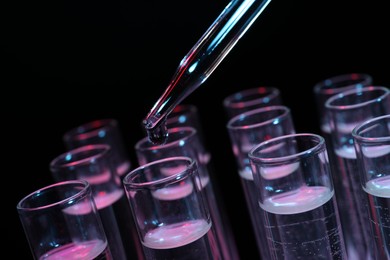 Photo of Dripping reagent into test tube on black background, closeup. Laboratory analysis