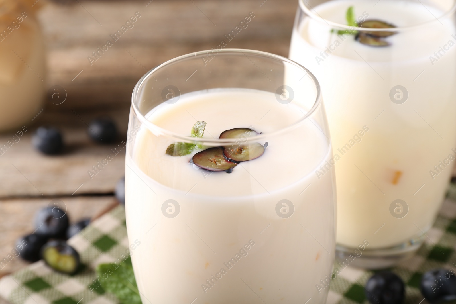 Photo of Tasty yogurt in glasses and blueberries on table, closeup