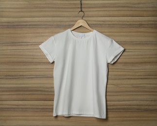 Photo of Hanger with stylish white T-shirt on wooden wall