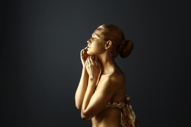 Portrait of beautiful lady with gold paint on skin against grey background