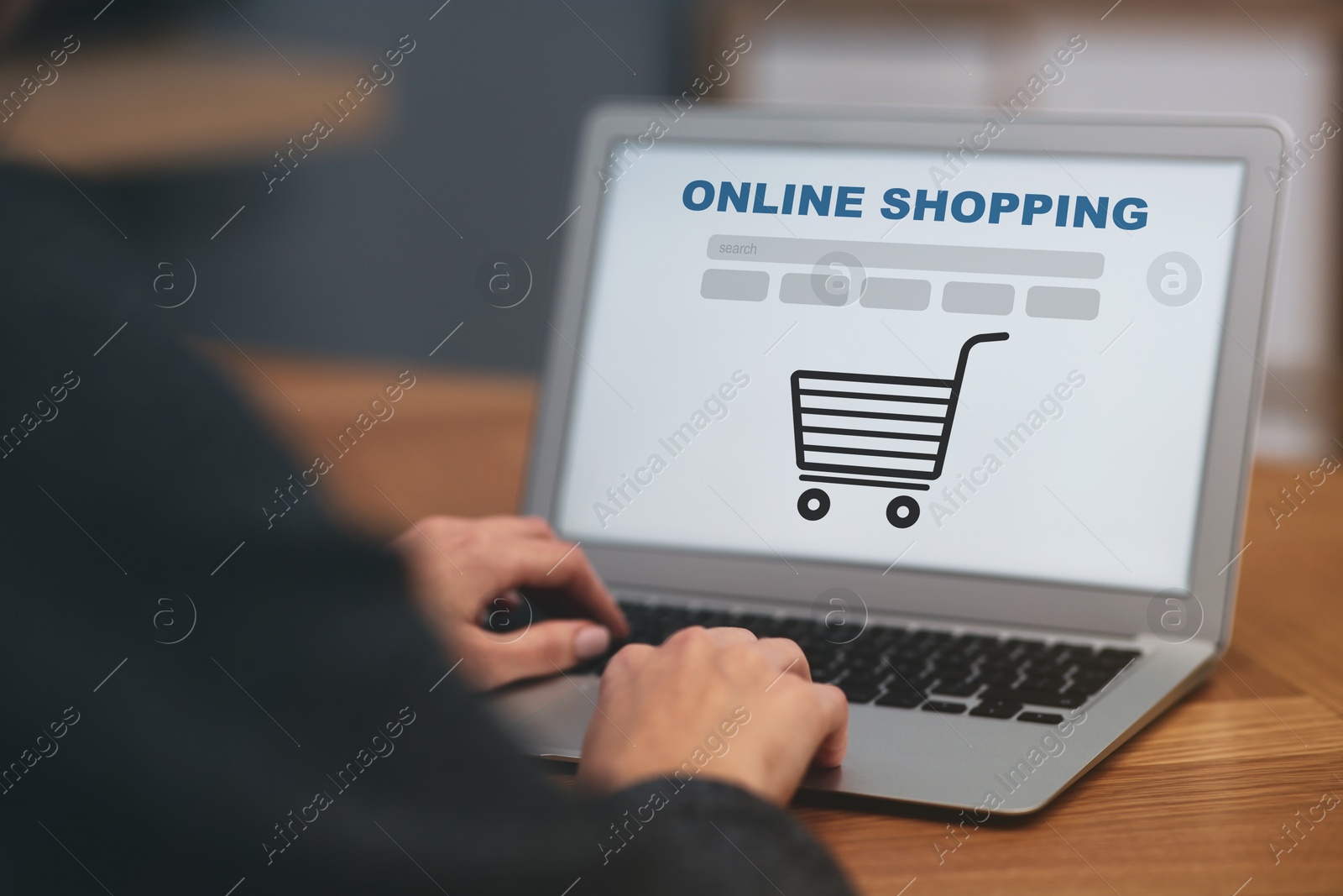 Image of Woman using laptop for online shopping at wooden table, closeup