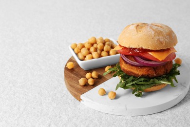 Tasty vegetarian burger with chickpea cutlet on white table, space for text