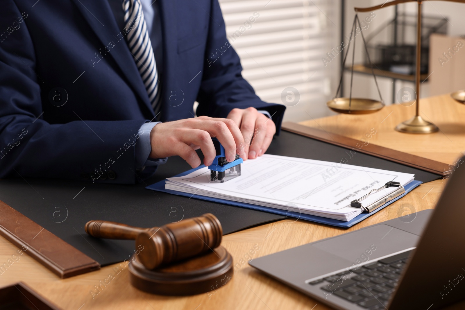 Photo of Notary stamping document at wooden table in office, closeup