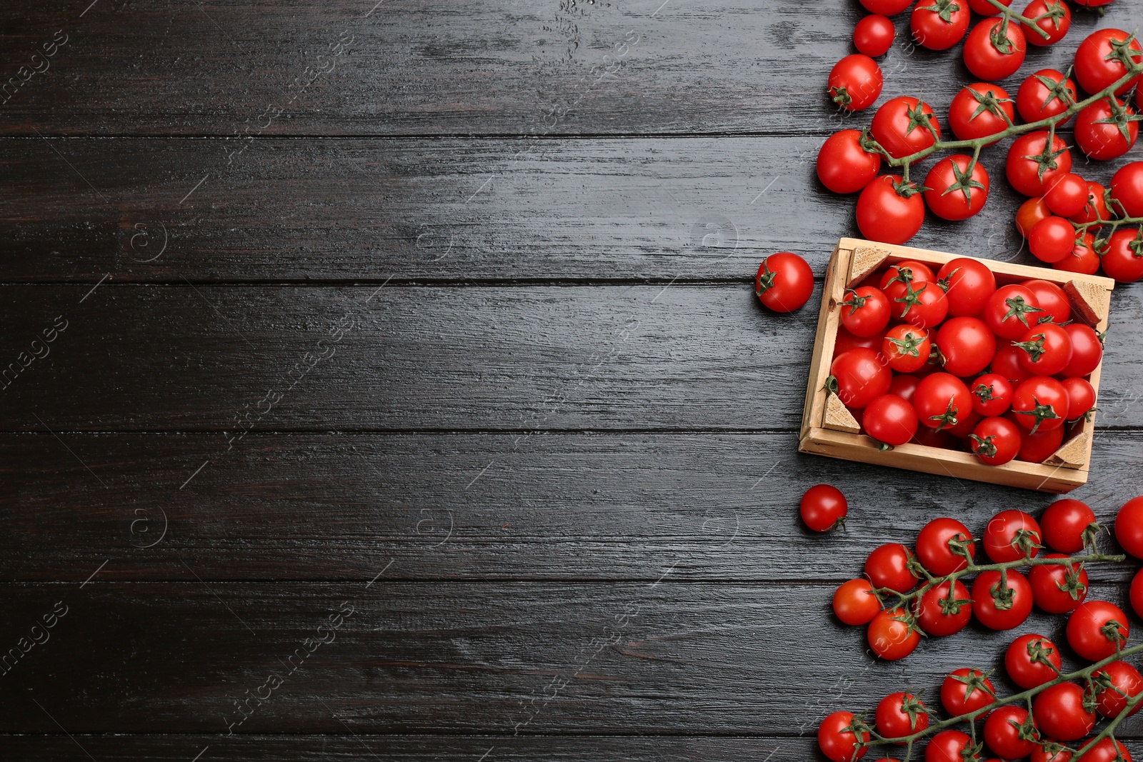 Photo of Fresh cherry tomatoes and crate on black wooden table, flat lay. Space for text