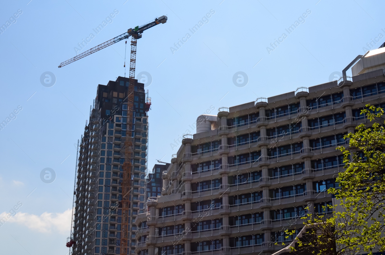 Photo of Beautiful modern building and tower crane against blue sky