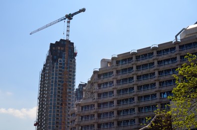 Photo of Beautiful modern building and tower crane against blue sky