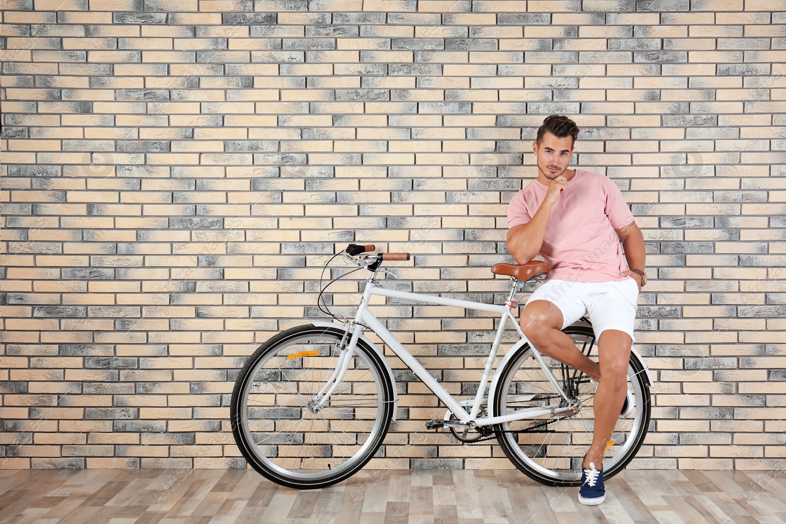 Photo of Handsome young hipster man with bicycle near brick wall