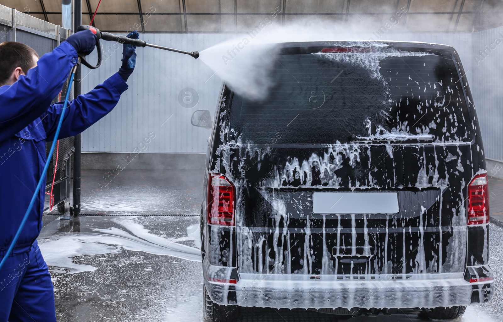 Photo of Worker cleaning automobile with high pressure water jet at car wash