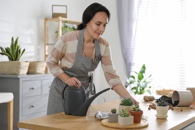 Photo of Mature woman watering houseplants at home. Engaging hobby