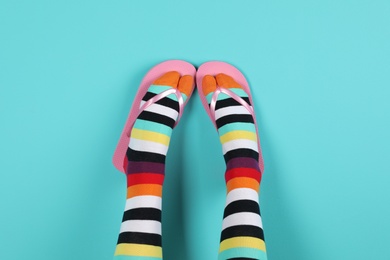 Photo of Woman wearing bright socks with flip-flops on color background