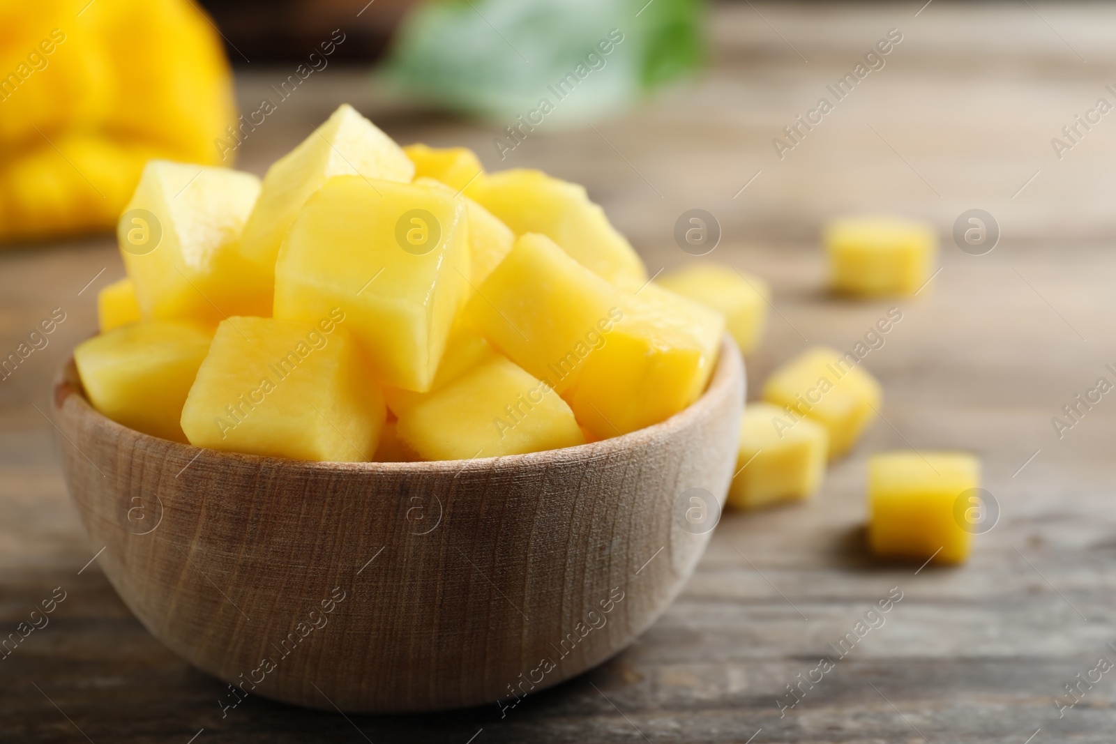 Photo of Cubes of fresh ripe mango in bowl on wooden table