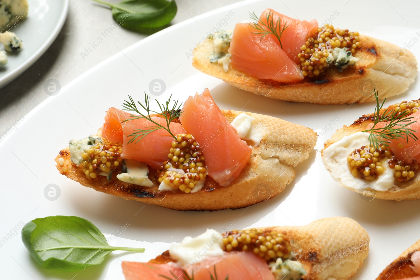 Photo of Tasty bruschettas with salmon and blue cheese on plate, closeup