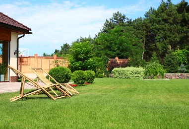 Wooden deck chairs in garden on sunny day