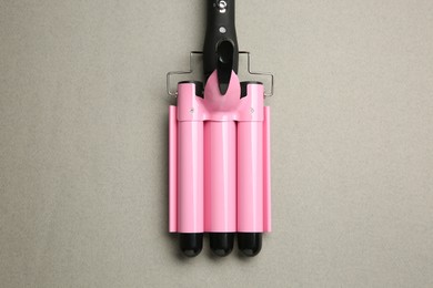 Photo of Modern triple curling hair iron on grey background, top view