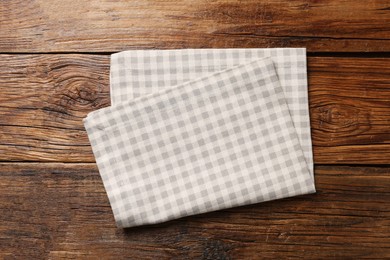 Photo of Beige checkered tablecloth on wooden table, top view
