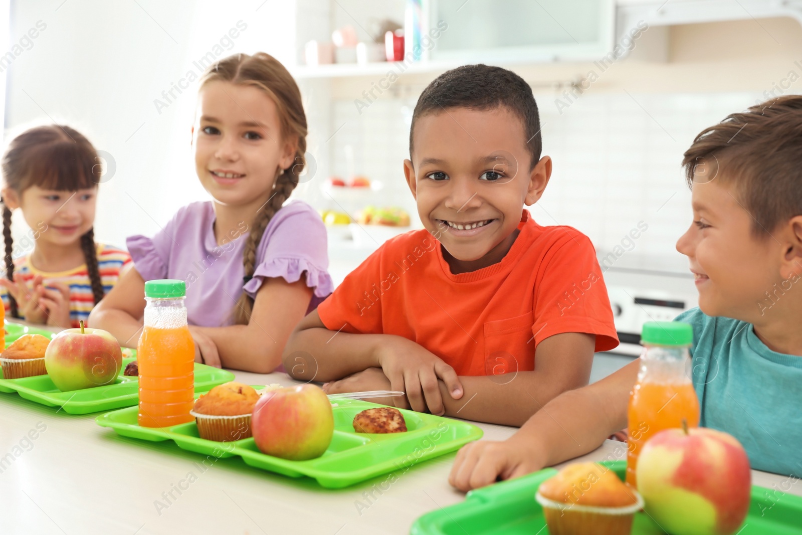 Photo of Children sitting at table and eating healthy food during break at school