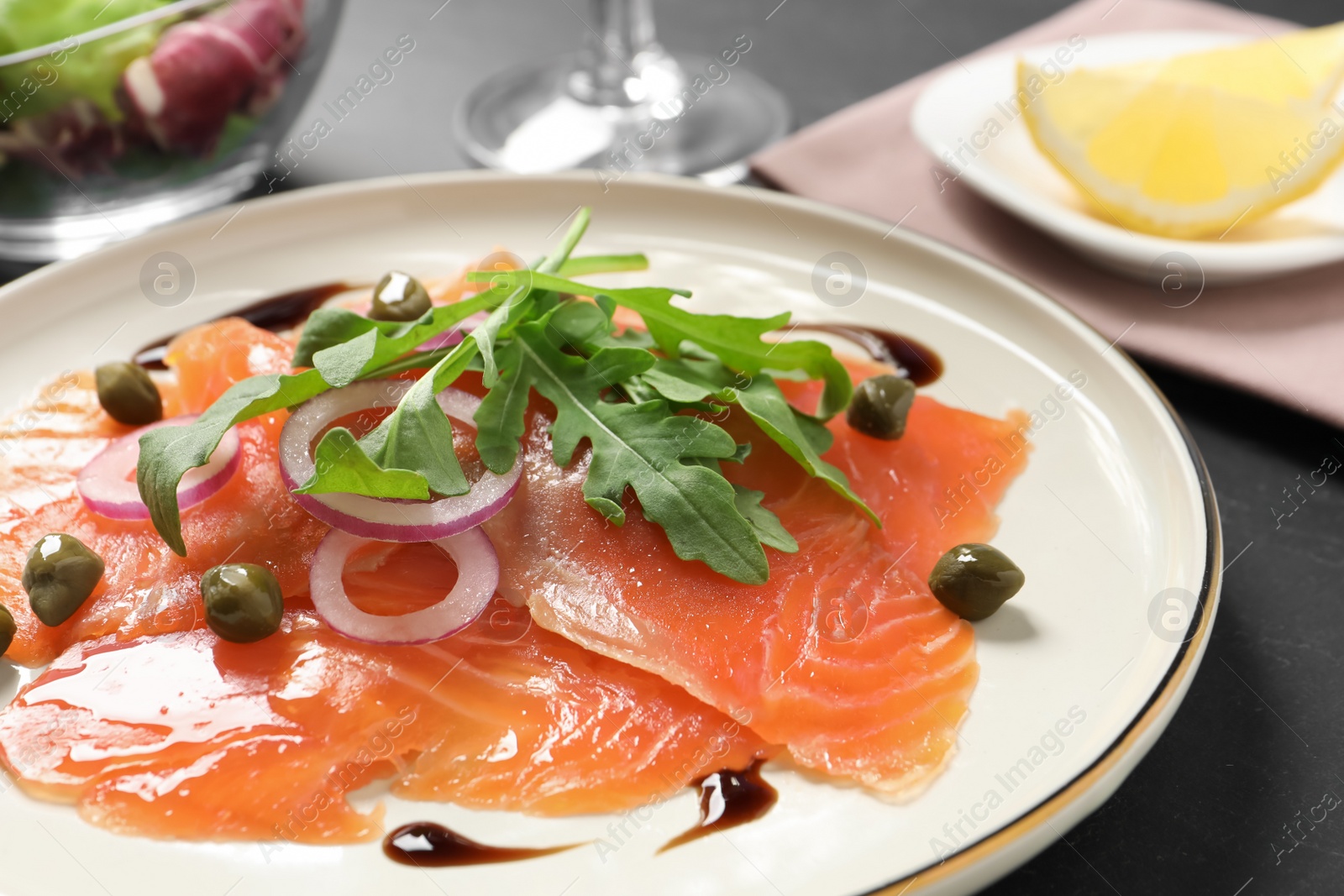 Photo of Delicious salmon carpaccio served on black table, closeup