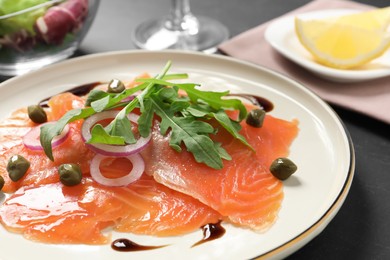 Photo of Delicious salmon carpaccio served on black table, closeup