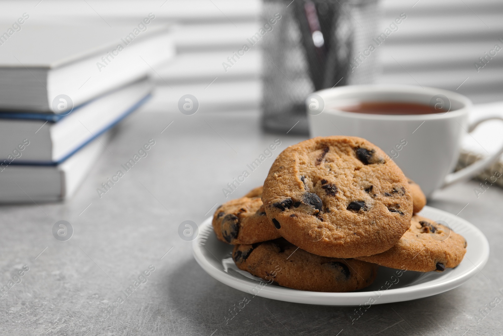 Photo of Chocolate chip cookie on light grey table in office, closeup. Space for text