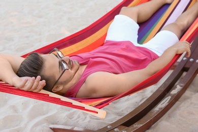 Photo of Young man resting in colorful hammock at seaside