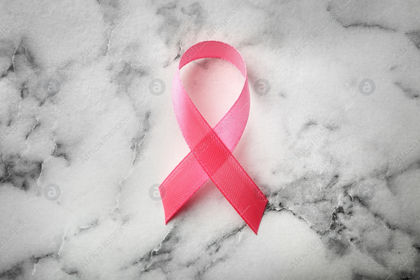 Photo of Pink ribbon on marble background, top view. Breast cancer awareness concept