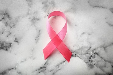 Pink ribbon on marble background, top view. Breast cancer awareness concept