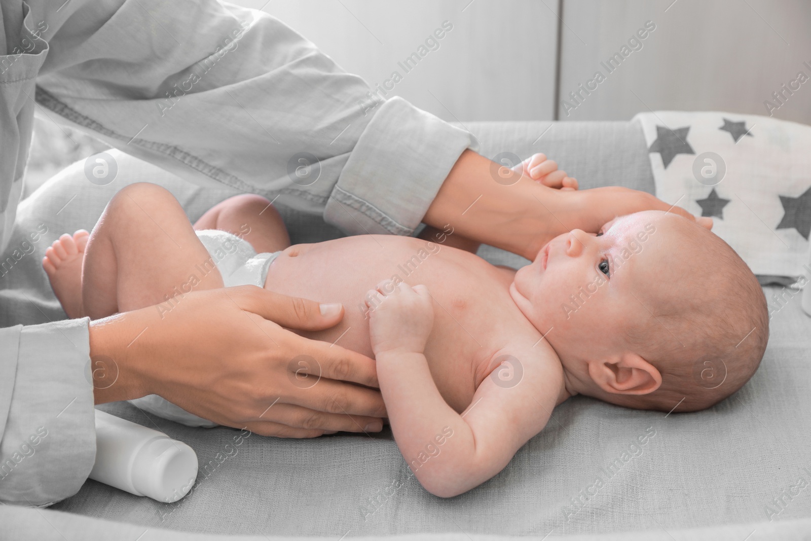 Photo of Mother taking care of her baby on changing table indoors, closeup