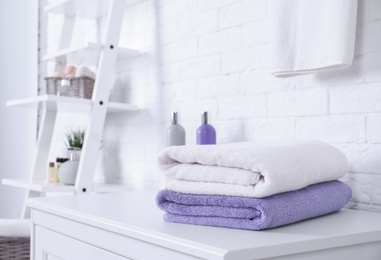 Photo of Stack of fresh towels on table in bathroom. Space for text