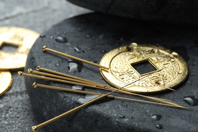 Photo of Acupuncture needles, Chinese coin and stone with water drops on grey textured table, closeup