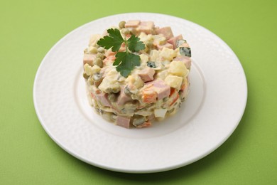 Photo of Tasty Olivier salad with boiled sausage on green table