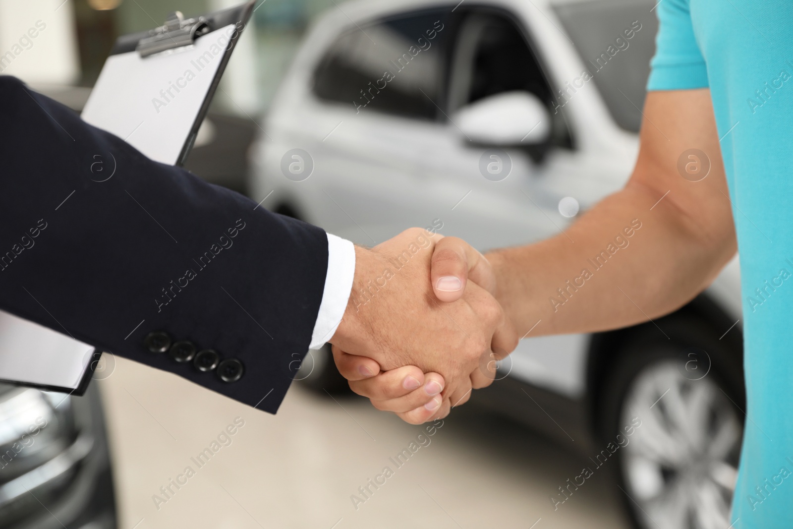 Photo of Customer and salesman shaking hands in car salon