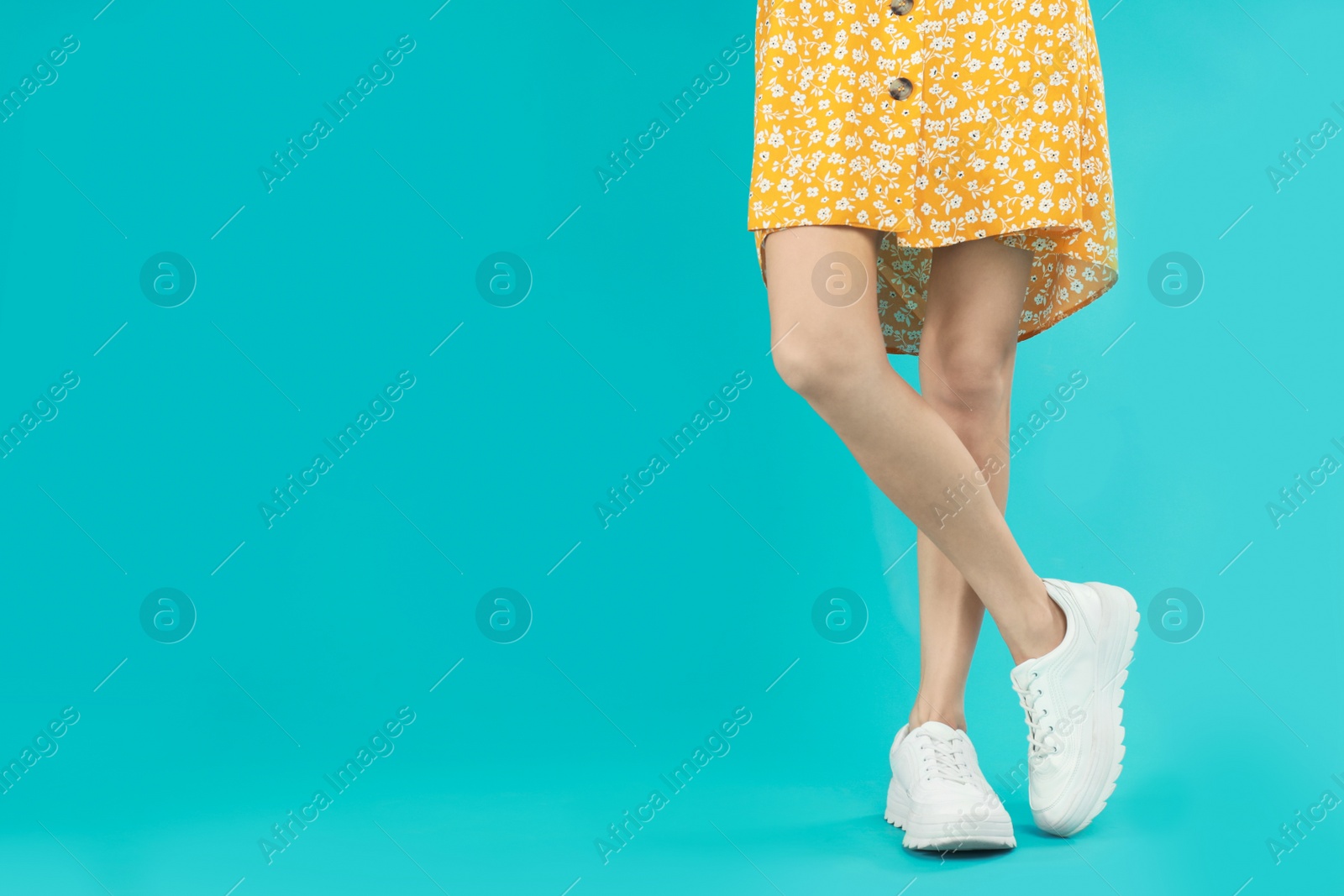 Photo of Woman in stylish sport shoes on light blue background. Space for text